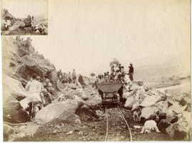 Workers pushing trolley with rocks in cutting.