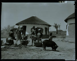 Transkei, 1968. Group of people around pots in kraal.