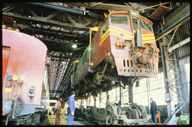 
SAR Class 6E1 Srs 5 suspended over undercarriage in workshop.

