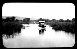 Round in Nine Tours - two motor cars crossing wide water body.