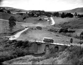 "1951. Two SAR buses on country road with bridge, with a settlement in the distance."
