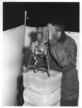 Chamelsbaai, 1962. Surveyor taking a theodolite reading.