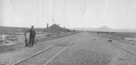 Baroda, 1895. Railwayman at points with station building in distance. (EH Short)