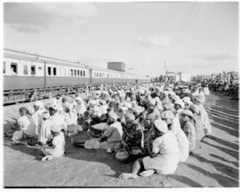 Bechuanaland, 17 April 1947. Crowd seated alongside Pilot Trains at wayside station.