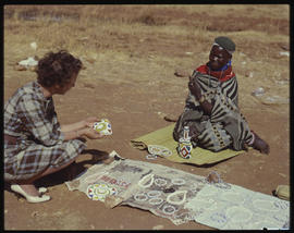 
Woman inspecting beadwork from street vendor.
