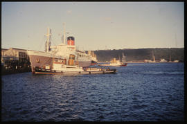 Durban. SAR tug with 'Pendennis Castle' leaving Durban Harbour.