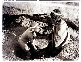 Transkei, 1940. Removing mealies from natural storage bin.