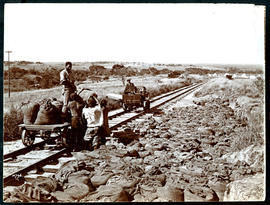Construction and inspection trolleys on railway line with tented construction camp in the distance.