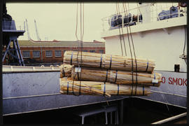 Loading rolls of timber into ship hold.
