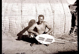 Natal, 1935. Zulu warrior in front of hut.