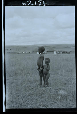 Transkei, 1954. Two young boys with kraal in the distance.