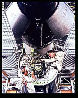 Three mechanics working on Boeing 727 aircraft engine.
