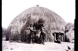 Natal. Three Zulu women and baby outside hut.