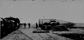Kraankuil, 1895. Train at loading platform and ramp with three men posing. (EH Short)
