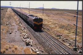 
SAR Class 7E No E7025 with passenger train in open country.
