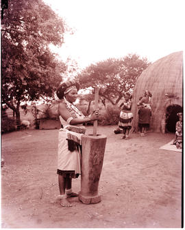 "Pietermaritzburg district, 1966. Zulu woman grinding mealies at traditional hut."