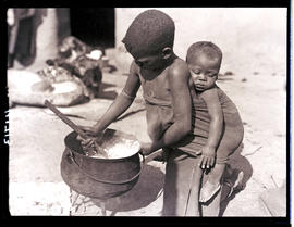 Transkei, 1932. Young boy stirring cooking pot.