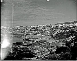 Hermanus, 1948. Rugged coastline with village in the distance.
