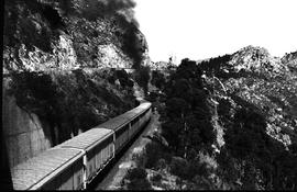 
Goods train entering tunnel with road above.
