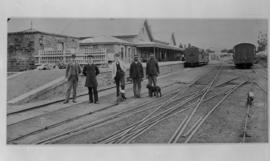 Grahamstown, 1895. Stationmaster and staff with station building in the distance. [EH Short]