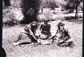 Natal. Zulu traditional healer with two women sitting on grass.