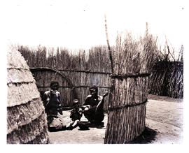 Natal. Two Zulu women and baby in reed enclosure.
