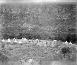 Page 24. construction camp in distance with tents and wagons. Four well dressed men relaxing in f...