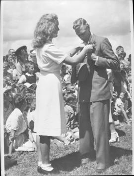 Pietersburg, 3 April 1947. Young woman pins a corsage onto King George VI's suit.