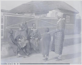 Pretoria district, 1952. Ndebele women and children sitting on bench in kraal.