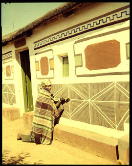 Pretoria district. Ndebele woman decorating traditional home.