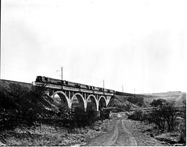 Vryheid district, 1978. SAR Class 34-600 heading five other locomotives and goods train over bridge.