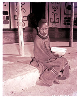 "1951. Young Ndebele child with bowl in front of hut."