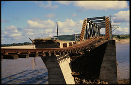 Damaged bridge over wide river.