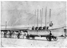 Rowing boat on trailer drawn by white horses.