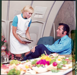 SAA Boeing 747 interior, hostess handing out magazines.