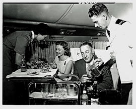 
SAA Douglas DC-7B interior, cabin steward serving dinner.
