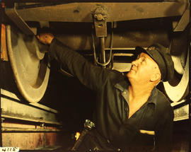 Checking the undercarriage of a railway wagon.