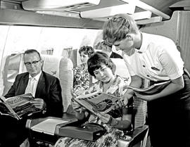 
SAA Boeing 707 interior. Hostess handing out magazines. See C6023.
