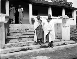 Tzaneen district, 1946. Queen Modjadji, Rain Queen with an elder on steps of a farm house.