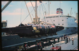 Durban, 1973. Offloading heavy equipment from ship onto cradle in Durban Harbour. [Willem van der...