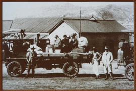 Passengers and luggage on old motor truck.