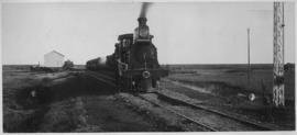 Taung, 1895. Cape 3rd Class Dubs locomotive with train at station. (EH Short)
