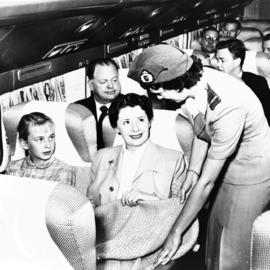 
SAA Douglas DC-7B interior. Hostess handing blanket to passenger.
