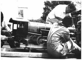 Men loading model locomotive.