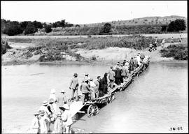 Estcourt district, 1922. Group of well-dressed people crossing river on makeshift bridge of ox wa...