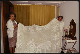 Two women holding bedcloth.