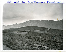 Cape Province, 1956. Electrical locomotive with passenger trains approaching cutting.
