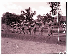 
Army recruits in training, rifle practice with gas masks.
