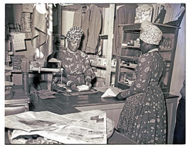Windhoek, Namibia, 1952. Herero woman serving customer in her store.