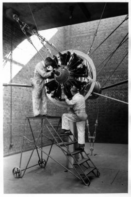 SAA technicians working on aircraft radial engine in engine test house.